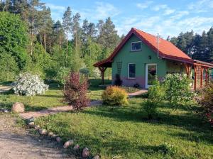 ein grünes Haus mit rotem Dach im Hof in der Unterkunft Zielona Chatka pod Srebrnym Żurawiem in Wydminy
