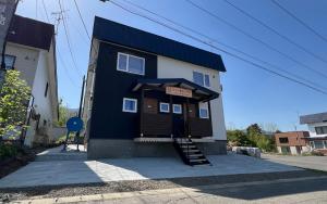 Furano Yukisachi House في فورانو: مبنى باللونين الأزرق والأبيض مع وجود علامة عليه