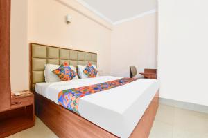 sypialnia z dużym białym łóżkiem z kolorowymi poduszkami w obiekcie FabExpress Central Plaza w mieście Dehradun