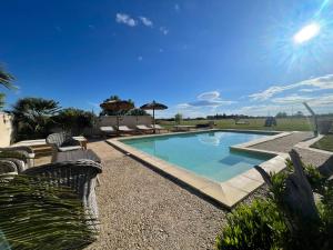 a swimming pool in a yard with chairs and an umbrella at MAS DES PAZ in Aigues-Mortes