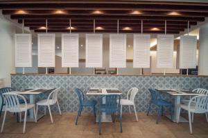 une salle à manger avec des tables, des chaises et des cheminées blanches dans l'établissement Hotel - Bungalows Don Juan Tossa, à Tossa de Mar
