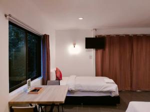 1 dormitorio con cama, mesa y ventana en THANSILA Resort, en Ranong