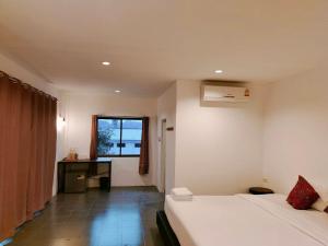 Habitación con 2 camas, escritorio y ventana. en THANSILA Resort, en Ranong