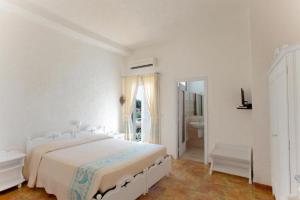 een witte slaapkamer met een bed en een badkamer bij HOTEL AL FARO spiaggia la Cinta SanTeodoro in San Teodoro