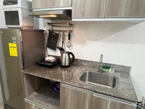 a small kitchen with a sink and a refrigerator at Grand stay in Cebu City