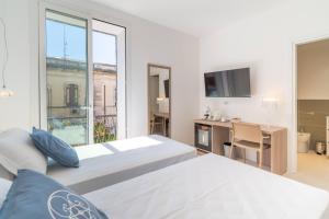 a bedroom with two beds and a desk and a window at Dimore delle Zagare Molo in Syracuse