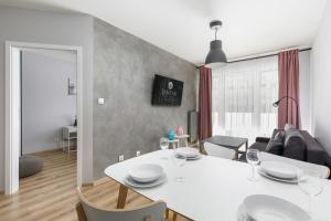 uma cozinha e sala de estar com uma mesa branca e cadeiras em Jantar Apartamenty Kołobrzeg - Kasprowicza 20 Swimming Pool em Kolobrzeg