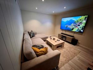 a living room with a couch and a flat screen tv at StarView Trolltunga Apartment in Odda