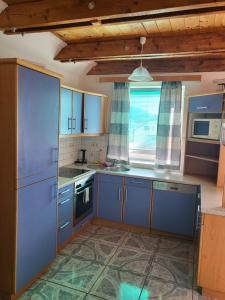 eine Küche mit blauen Schränken und einem großen Fenster in der Unterkunft Ferienwohnung 123 in Fohnsdorf