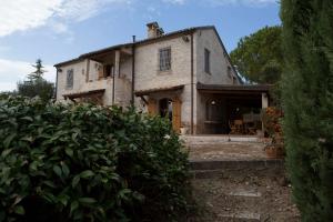 una antigua casa de piedra con un jardín delante de ella en Villa Anna - Homelike Villas, en Montone