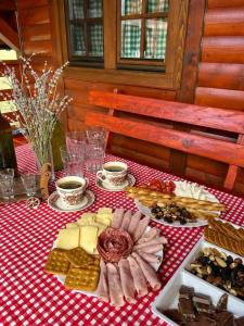 un tavolo con formaggio e altri prodotti alimentari su una tovaglia rossa e bianca di Ranč Crna stina a Livno