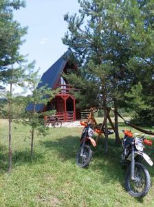 two motorcycles parked in the grass in front of a cabin at Ranč Crna stina in Livno