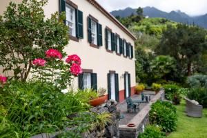 um edifício com flores cor-de-rosa e bancos num quintal em Casa Da Piedade em São Vicente