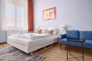 1 dormitorio con 1 cama y 1 silla azul en Elys Aparthotel in Leipzig - Vollausgestattete Apartments mit Netflix, en Leipzig