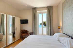 Un dormitorio con una gran cama blanca y una ventana en Grand Hotel Mediterranee, en Alassio