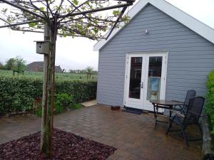 a small gray house with a table and a patio at Room by the sea in Zoutelande