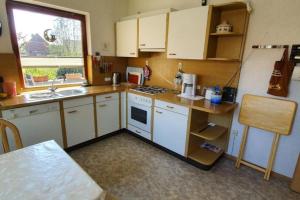 uma cozinha com armários brancos, um lavatório e um frigorífico em Haus Minor em Borkum