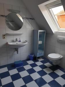 een badkamer met een wastafel, een toilet en een spiegel bij Huus 24 in Borkum