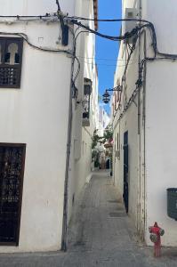 an alley with white buildings and a red fire hydrant at Bab El Fen in Tangier