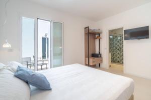 a white bedroom with a bed and a balcony at Dimore delle Zagare Molo in Syracuse