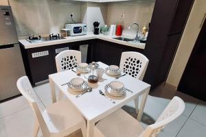 - une table et des chaises blanches dans la cuisine dans l'établissement Poolside Haven: 2BR Garden Oasis, à Johor Bahru