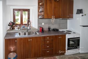 eine Küche mit Holzschränken, Spüle und Herd in der Unterkunft Iasona's House in Agios Georgios Nileias