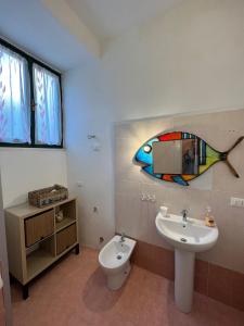 baño con lavabo y una pintura de pescado en la pared en Le petit refuge en Capraia