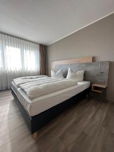 1 dormitorio con 1 cama grande con sábanas y almohadas blancas en Rheinhessen Inn GmbH, en Wörrstadt