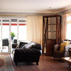 a living room with a leather couch and chairs at Waterfront Delight in Knysna
