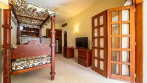 une chambre avec un lit à baldaquin et une télévision dans l'établissement Tembo Beach Apartments, à Malindi