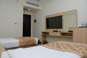um quarto de hotel com duas camas e uma televisão de ecrã plano em فندق ريست ان em Qabāʼ