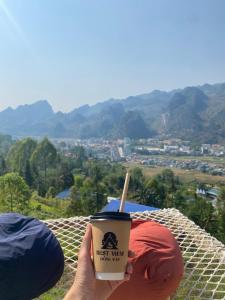 een persoon met een kopje koffie en uitzicht bij Best View Đồng Văn in Ha Giang