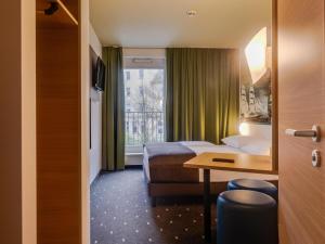 a hotel room with a bed and a desk and a window at B&B Hotel Bremerhaven in Bremerhaven