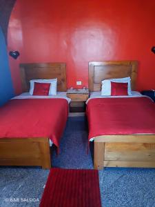 2 Betten in einem Zimmer mit roten Wänden in der Unterkunft B&B Saluga Sehel Island Nubian House in Assuan