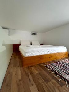 een slaapkamer met een groot bed met witte lakens bij Vourtaréa Guesthouse in Himare