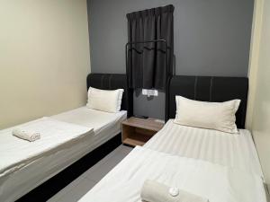 two beds in a small room with white sheets at Gebeng Industrial Park Budget Hotel in Kuantan