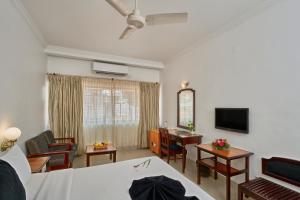 Sala de estar con cama, escritorio y TV en Abad Fort, en Kochi