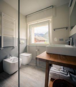 baño con lavabo y aseo y ventana en l'Oura B&B en Challand Saint Anselme