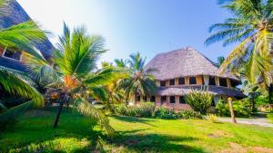 a house with palm trees in front of it at Tembo Oceanic Apartments in Malindi