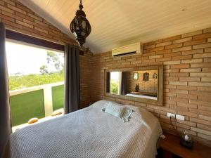 1 dormitorio con cama y pared de ladrillo en Villa Villagio di Mare, en Ilhabela