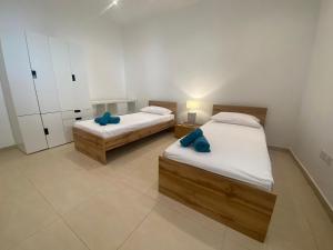 - 2 lits dans une chambre avec 2 oreillers bleus dans l'établissement St Julians Apt with Pool, à San Ġiljan