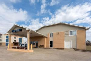 a front view of a building with a car dealership at Days Inn by Wyndham Ogallala in Ogallala