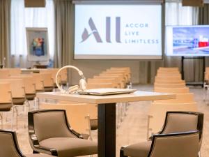 una sala de conferencias con sillas, mesa y pantalla en Novotel Nice Arenas Aeroport, en Niza