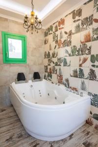 baño con una gran bañera blanca y una ventana verde en La Scala Luxury Villa Μikis Theodorakis with jacuzzi en Kárpatos