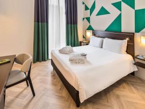una camera d'albergo con un grande letto e asciugamani di Mercure Napoli Centro Angioino a Napoli
