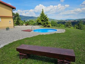 a bench sitting in the grass next to a small pool at Holiday House Nika in Vrbovsko