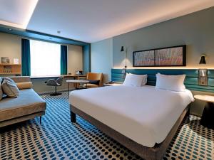 una camera d'albergo con un grande letto e un divano di Novotel Luxembourg Kirchberg a Lussemburgo