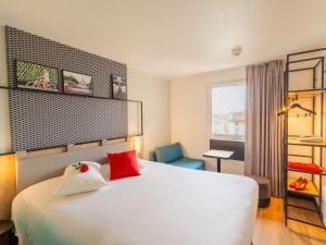 a hotel room with a white bed and a chair at ibis Paris Vanves Parc des Expositions in Vanves