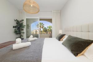 - une chambre blanche avec un grand lit et 2 chaises blanches dans l'établissement Apartment next to the beach in Hacienda Playa, Elviria, à Marbella