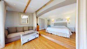 ein großes Schlafzimmer mit einem Bett und einem Sofa in der Unterkunft La Petite Auberge in Tourtour